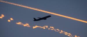Ein Passagierflugzeug zwischen zwei von der Sonne gefärbten Kondensstreifen. 