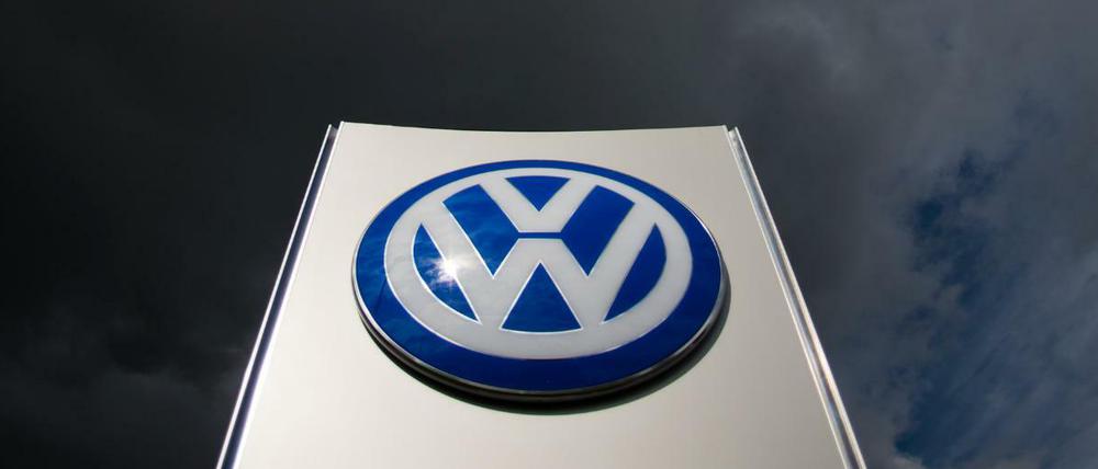 Dunkle Wolken ziehen über ein VW-Logo am Tor Sandkamp vom VW Werk in Wolfsburg hinweg.