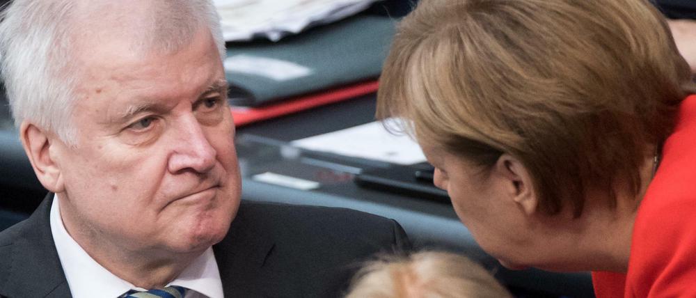 Horst Seehofer (CSU), Bundesminister für Inneres, und Bundeskanzlerin Angela Merkel (CDU) unterhalten sich bei der Plenarsitzung im Deutschen Bundestag.