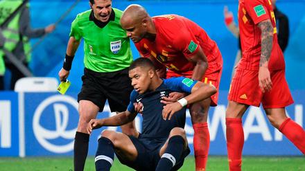 Belgiens Vincent Kompany hebt Kylian Mbappé wieder auf – Schiedsrichter Andres Cunha wartet mit der gelben Karte.