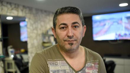 Der Friseurs Özlan Yildirim steht in seinem Laden. Yildirim ist ein Opfer der Nagelbombe, die der NSU in der Keupstraße explodieren ließ. +