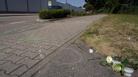 Mit grünen Markierungen hat die Polizei nach einem schweren Verkehrsunfall Spuren gekennzeichnet. Daneben sind Blumen und Kerzen abgelegt worden. 
