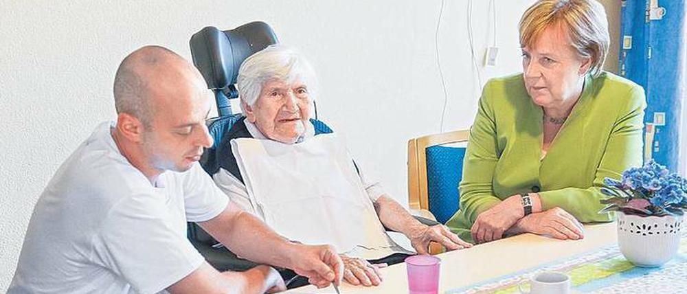 Versprechen gehalten. Die Kanzlerin mit Pfleger Cebi im Heim. 