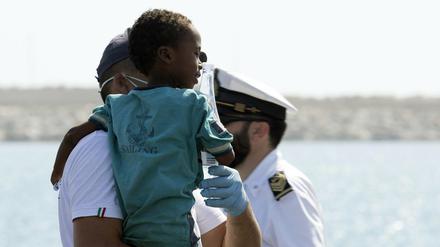 Ein Sanitäter hält ein Kind, nachdem dieses von Bord eines Schiffes der italienischen Küstenwache ging. 