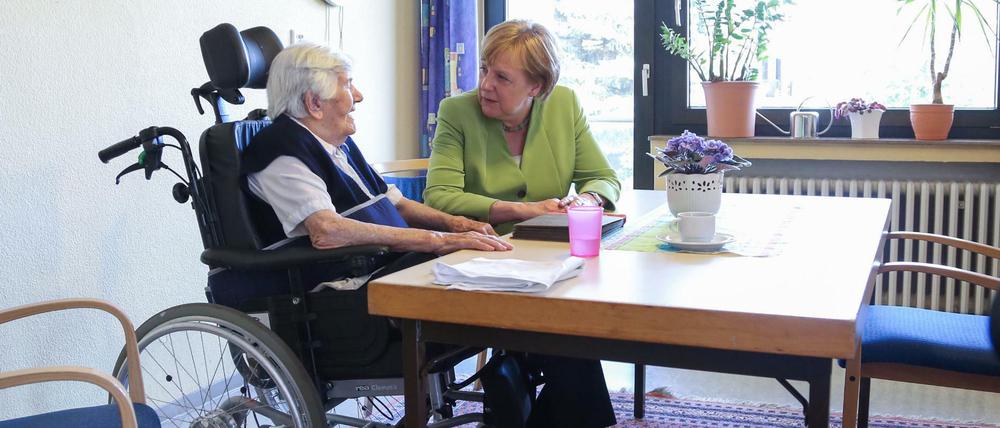Bundeskanzlerin Angela Merkel (CDU) besucht das Altenheim St. Johannisstift in Paderborn und spricht mit einer Bewohnerin.