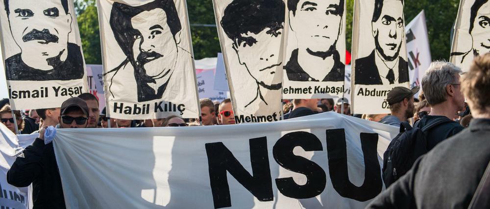 Demonstrierende halten bei einer Kundgebung Schilder mit Porträts der NSU-Opfer.