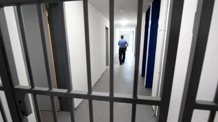 Hessen, Darmstadt: Ein Justizbeamter geht hinter einer vergitterten Tür über den Flur eines Zellentrakts der Abschiebehafteinrichtung.