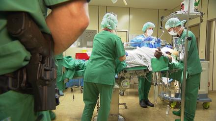 Mit Skalpell und Dienstwaffe. Die Ärzte und Krankenschwestern im Klinikum Frankfurt Höchst lassen sich bei der OP eines Straftäters auch nicht von einem bewaffneten Beamten mit Waffe beeindrucken. 