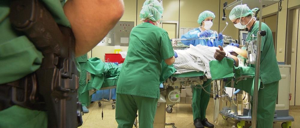 Mit Skalpell und Dienstwaffe. Die Ärzte und Krankenschwestern im Klinikum Frankfurt Höchst lassen sich bei der OP eines Straftäters auch nicht von einem bewaffneten Beamten mit Waffe beeindrucken.