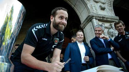 Hat gut lachen: Silvio Heinevetter (M.), Torhüter bei den Füchsen Berlin, beim Eintragen ins Goldene Buch des Bezirks Reinickendorf nach dem Gewinn des EHF-Pokals.