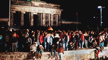Jubelnde Menschen standen am 09. November 1989 auf der Berliner Mauer vor dem Brandenburger Tor.