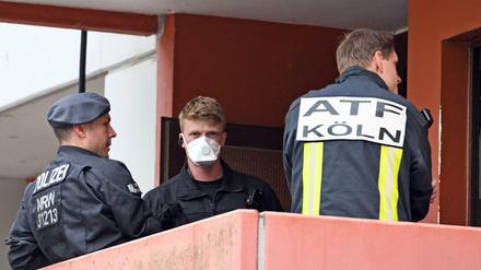 Polizisten und ein Feuerwehrmann stehen im Juni auf dem Balkon einer Wohnung in Köln-Chorweiler.