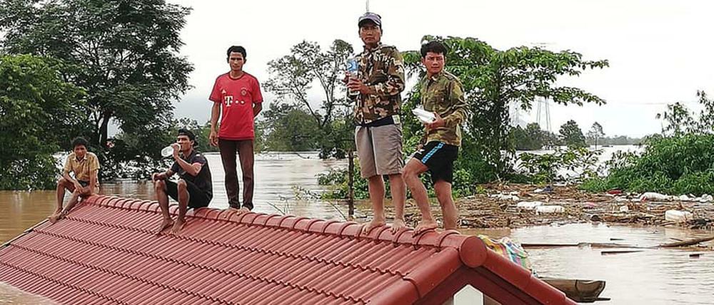 Laos, Attapeu: Dorfbewohner haben sich vor den Wassermassen auf die Dächer eines Hauses gerettet.