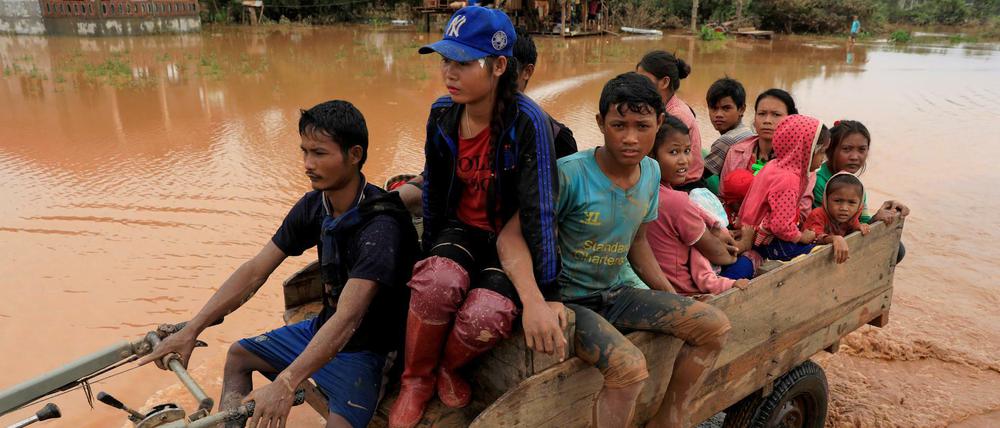 Menschen fahren auf einem Karren durch die Fluten.