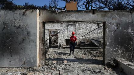 Griechenland, Mati: Ein Mitglied eines Rettungsteams sucht in einem ausgebrannten Haus nach Vermissten.