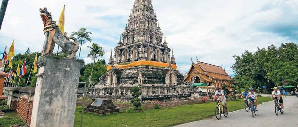 Auf einer Mountainbiketour radeln Touristen am Chedi Liam Temple in Chiang Mai vorbei.