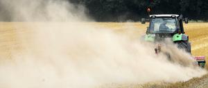 Ein Landwirt fährt mit einer Egge am Traktor über sein Feld und zieht eine Staubwolke hinter sich her. Die anhaltende Trockenheit bereitet den Bauern erhebliche Probleme.