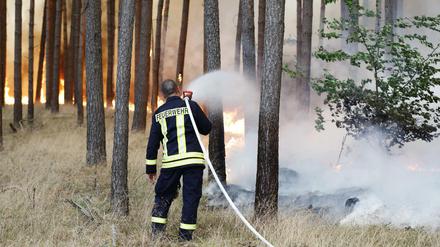Ein Feuerwehrmann bekämpft den Großbrand bei Fichtenwalde.