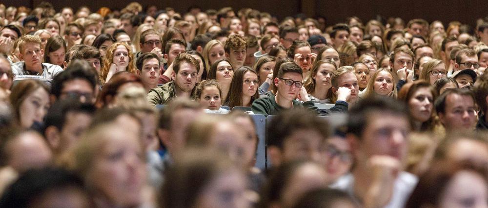 Studierende sitzen in einem vollbesetzten Hörsaal.