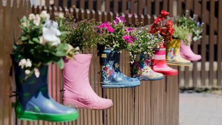 Gummistiefel mit Blumen am Zaun eines Kindergartens. 
