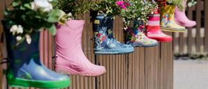 Gummistiefel mit Blumen am Zaun eines Kindergartens. 