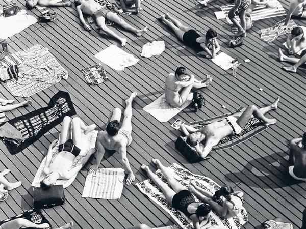 Sonnenbadende an einem Schwimmbecken in Paris.