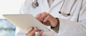 Ein Arzt mit Stethoskop um den Hals hantiert mit einem I-Pad.