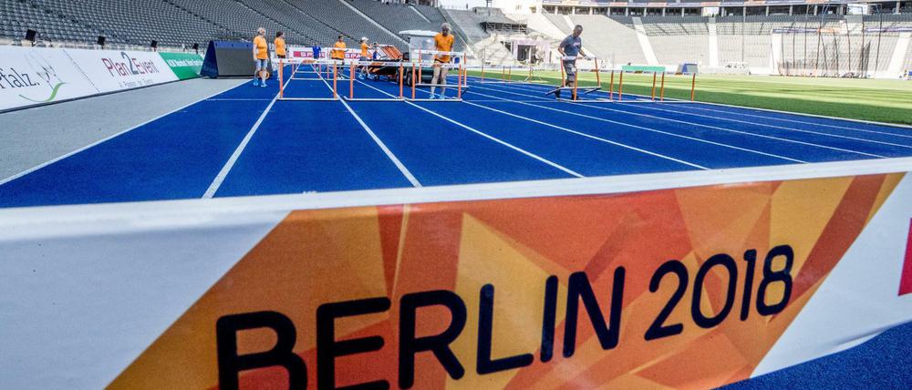 Helfer stellen bei den Vorbereitungen im Olympiastadion die Hürden auf der Laufbahn auf. 