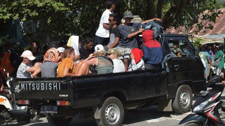 Touristen auf Lombok werden auf einem Pick up aus dem Erdbebengebiet gebracht.