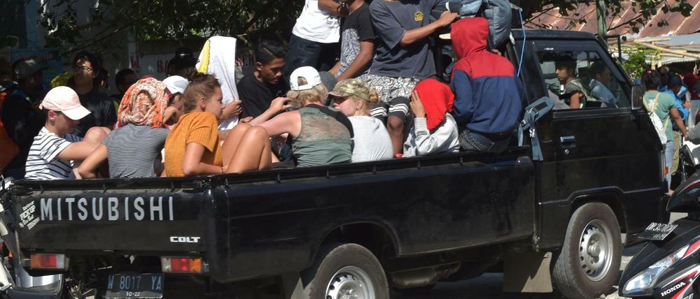 Touristen auf Lombok werden auf einem Pick up aus dem Erdbebengebiet gebracht.