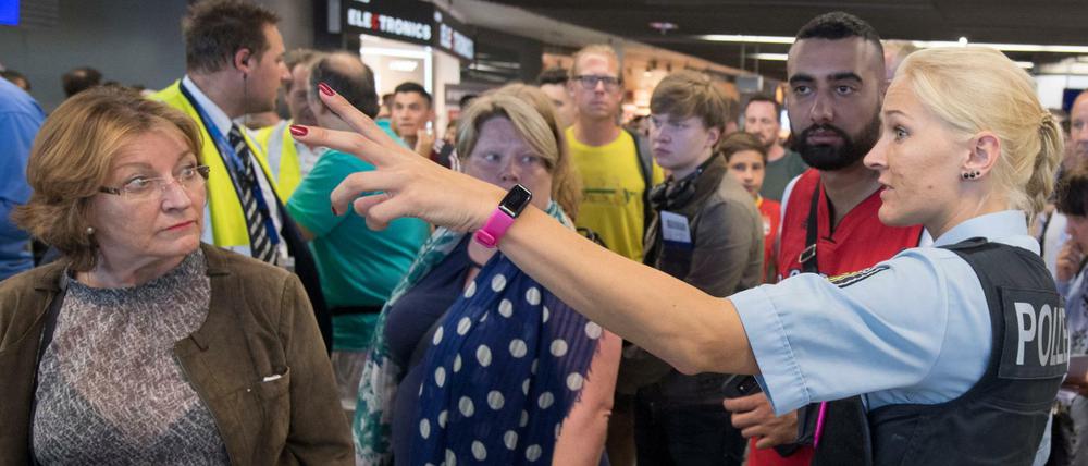 Eine Polizistin und Passagiere in Halle A im Terminal 1 des Flughafens Frankfurt