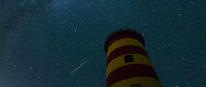 Eine Sternschnuppe leuchtet über dem Pilsumer Leuchtturm in Niedersachsen.