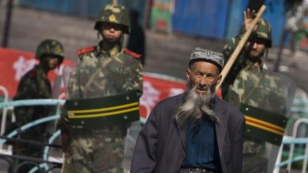 Ein Uigure geht in Ürümqi in der Unruheregion Xinjiang vorbei an chinesischen Sicherheitskräften.