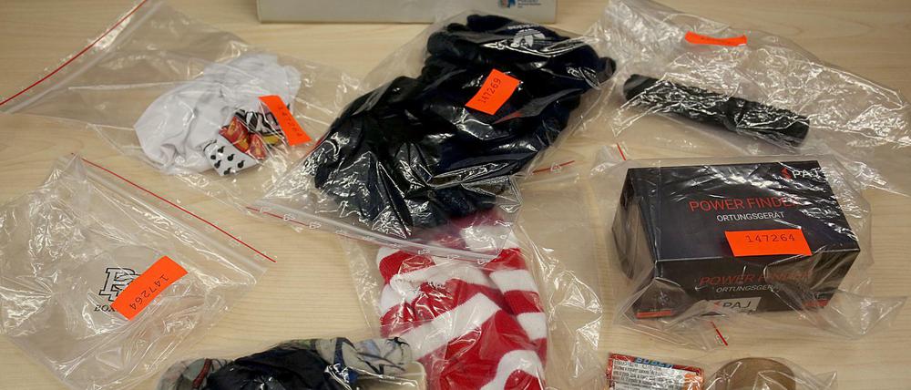 Sichergestellte Sturmhauben, pyrotechnisches Material, Schlagstöcke und ein Ortungsgerät liegen im Polizeipräsidium auf dem Tisch. Nach dem Angriff auf einen Fanbus des Fußball-Zweitligisten 1. FC Union Berlin in Köln hat die Polizei 28 Personen festgenommen. +