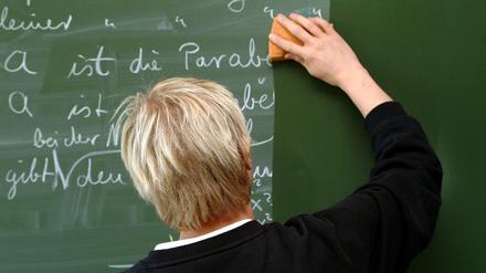 Ein Lehrer wischt eine Tafel.