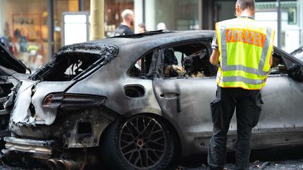 Ein Polizist steht am Mittwoch neben einem ausgebrannten Fahrzeug auf dem Kurfürstendamm. 
