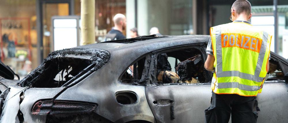 Ein Polizist steht am Mittwoch neben einem ausgebrannten Fahrzeug auf dem Kurfürstendamm. 