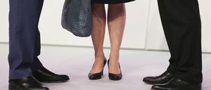 Eine Frau und zwei Männer stehen zusammen (Symbolbild).