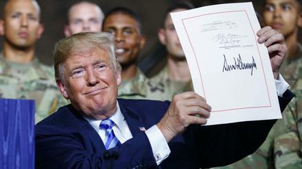 US-Präsident Donald Trump zeigt in der Militärbasis Fort Drum das frisch unterzeichnete Ausgabengesetz.