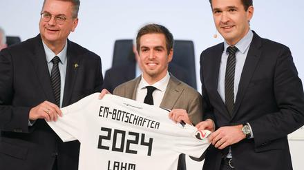DFB-Präsident Reinhard Grindel (l) und Generalsekretär Friedrich Curtius (r) überreichen dem neuen DFB-Ehrenspielführer Philipp Lahm ein Trikot.