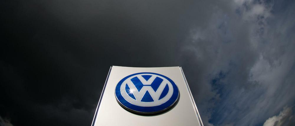 Dunkle Wolken über einem VW-Logo am Werk in Wolfsburg.