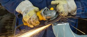 Ein Arbeiter im brandenburgischen Schwedt schleift mit einem Trennschneider an einem Rohr in einer Rohölverarbeitungsanlage.