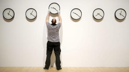 Ein Mitarbeiter wechselt in einer Ausstellung in der Talbot Rice Gallery eine Uhr aus.