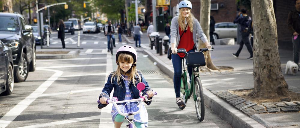 Portrait of mother and daughter riding bicycles on street