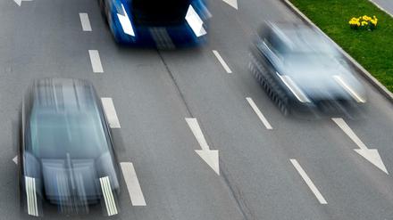 Autos rasen über eine dreispurige Straße.
