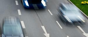 Autos rasen über eine dreispurige Straße.