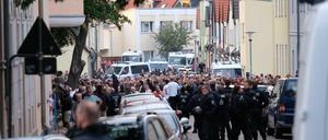 Menschen stehen umgeben von Polizisten in der Innenstadt von Köthen.