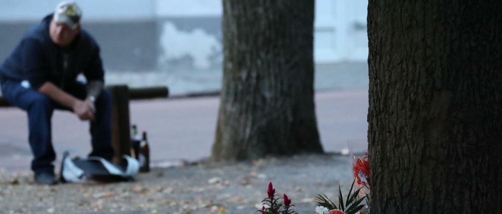 Ein Teilnehmer einer Kundgebung für einen verstorbenen 22-Jährigen sitzt auf einem Spielplatz neben Kerzen und Blumen.