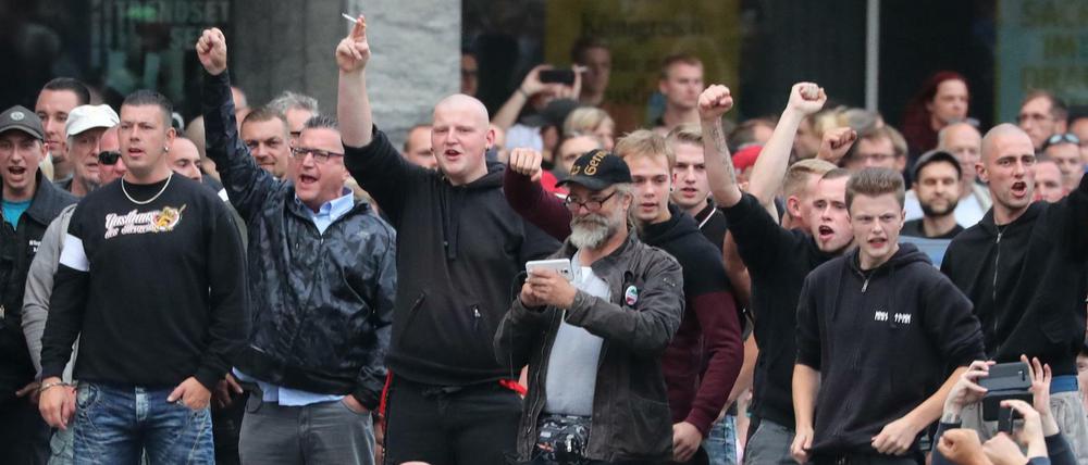 27.08.2018, Sachsen, Chemnitz: Rechte Demonstranten stehen vor dem Karl-Marx-Monument.
