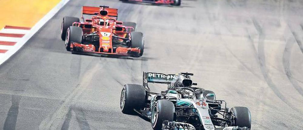Er fährt nur hinterher. Sebastian Vettel liegt sechs Rennen vor Schluss schon 40 Punkte hinter dem Führenden Lewis Hamilton (r.). In Singapur wählte sein Ferrari-Team die falsche Reifenstrategie, so dass er am Ende nur Dritter wurde. 
